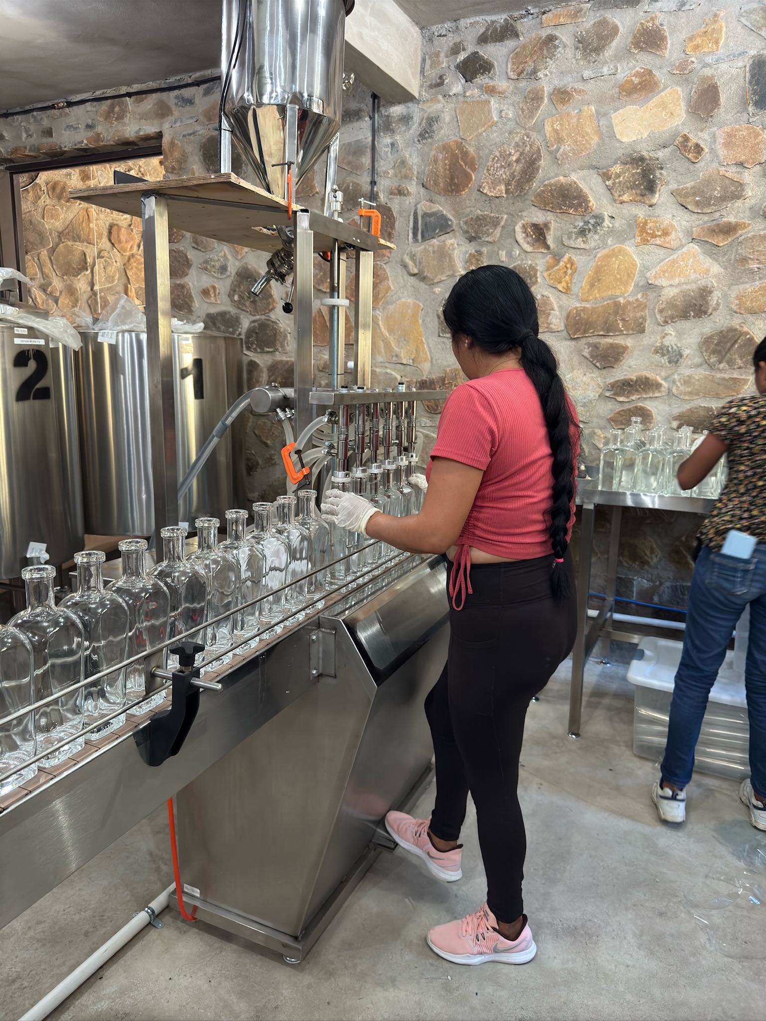 Mezcal Argato bottling process — team member operating the bottling line