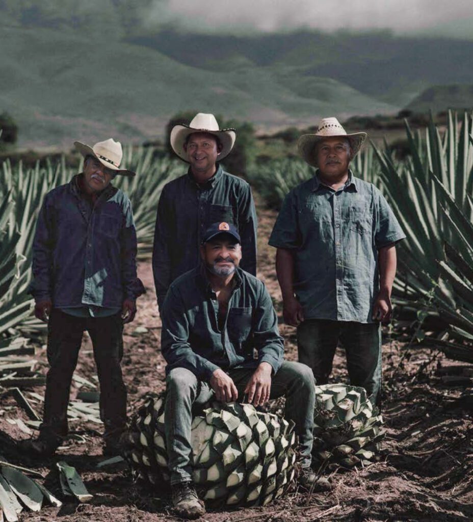 A group of men standing around some pineapples.